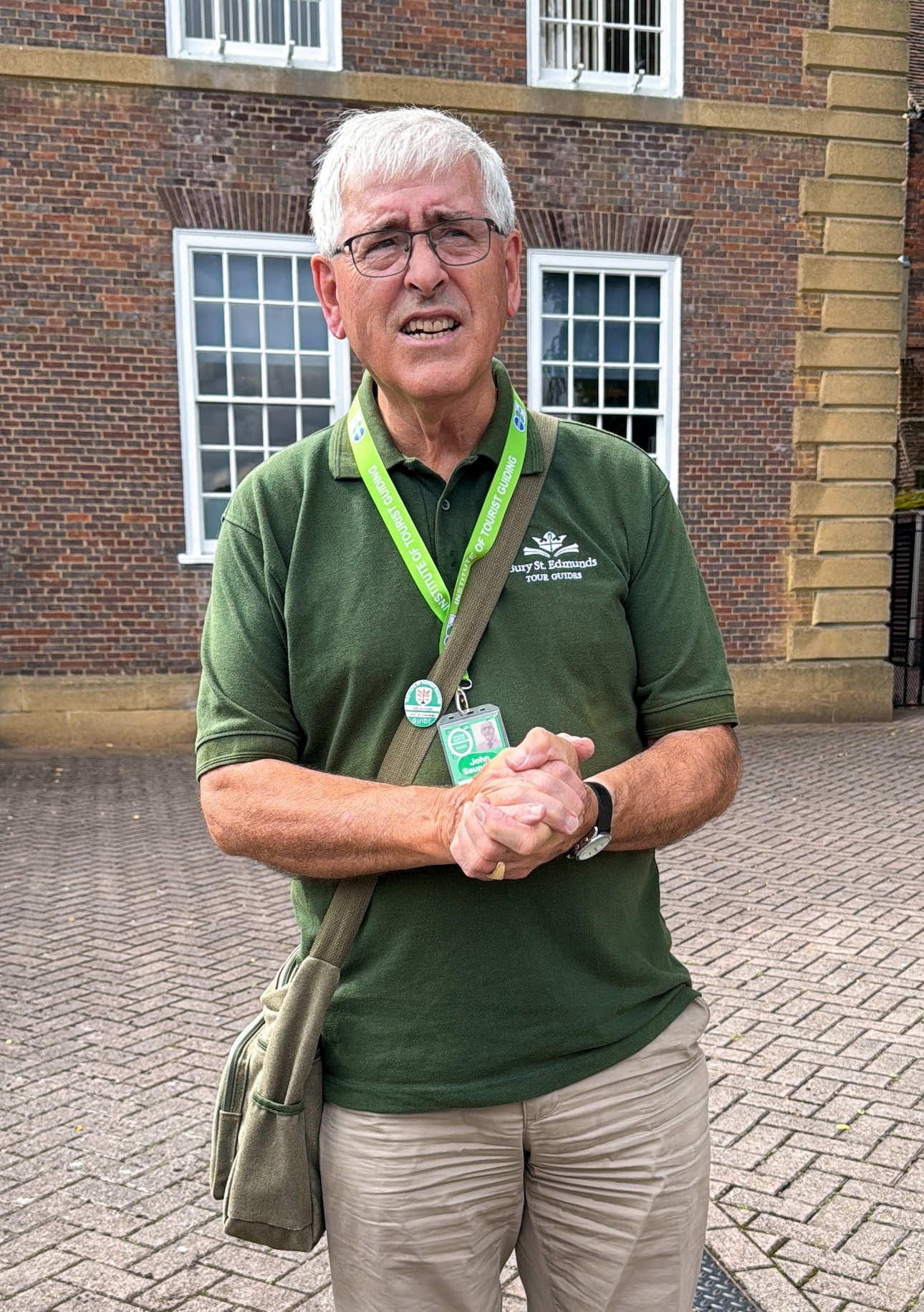 Suffolk, Bury St Edmunds, Male Tour Guide infront of Brick Building